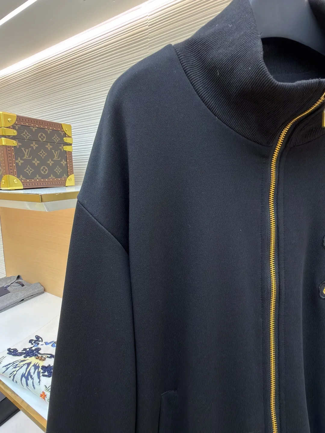 LOUIS VUITTON stand-up collar ribbed hem long-sleeved logo decorated jacket ●Original version: Purchased and developed at 25899 ●Item number: 1682404-B25 ●Fabric: cotton fabric ●Technology: knitted production ●Color: black ●Version: fitted version ●Weight: about 990 grams ●Size: S-M-L-XL ●Description: This Louis Vuitton stand-collar zipper jacket is made of high-thread-count cotton-elastic blended fabric, which has been treated with enzyme washing process. The fabric is soft to the touch and has good wrinkle resistance and elasticity. The body has a delicate matte texture. The LV logo on the chest uses a combination of gold thread embroidery and patchwork. The embroidery uses interlaced flat stitch and chain stitch techniques. The stitch density reaches 12 stitches per centimeter. The edges are overlocked and the pattern is three-dimensional and not easy to fall off. The jacket adopts a stand-up collar design, and the collar ribs are made of spandex blended material, which has been shaped to ensure that it will not loosen after long-term wear. The front is equipped with a custom brass zipper, and the zipper teeth are polished and gold-plated, making it smooth, wear-resistant and of high-quality texture. The side seam pockets are welted, and the seams are reinforced with double-needle sewing. The ribbed edges of the cuffs and hem are woven with high-elastic yarns of the same color. The shoulders are seamlessly spliced ​​with natural shoulder shapes. The overall craftsmanship combines the brand's classic elements with practical design, fully demonstrating the production level of high-end clothing. The overall wiring is straight and delicate, the fabric is comfortable and soft, and the color is consistent without color difference. It can be matched with the same style to create a fashionable look and control various occasions. Customized accessories, complete with three standards, same style for men and women!